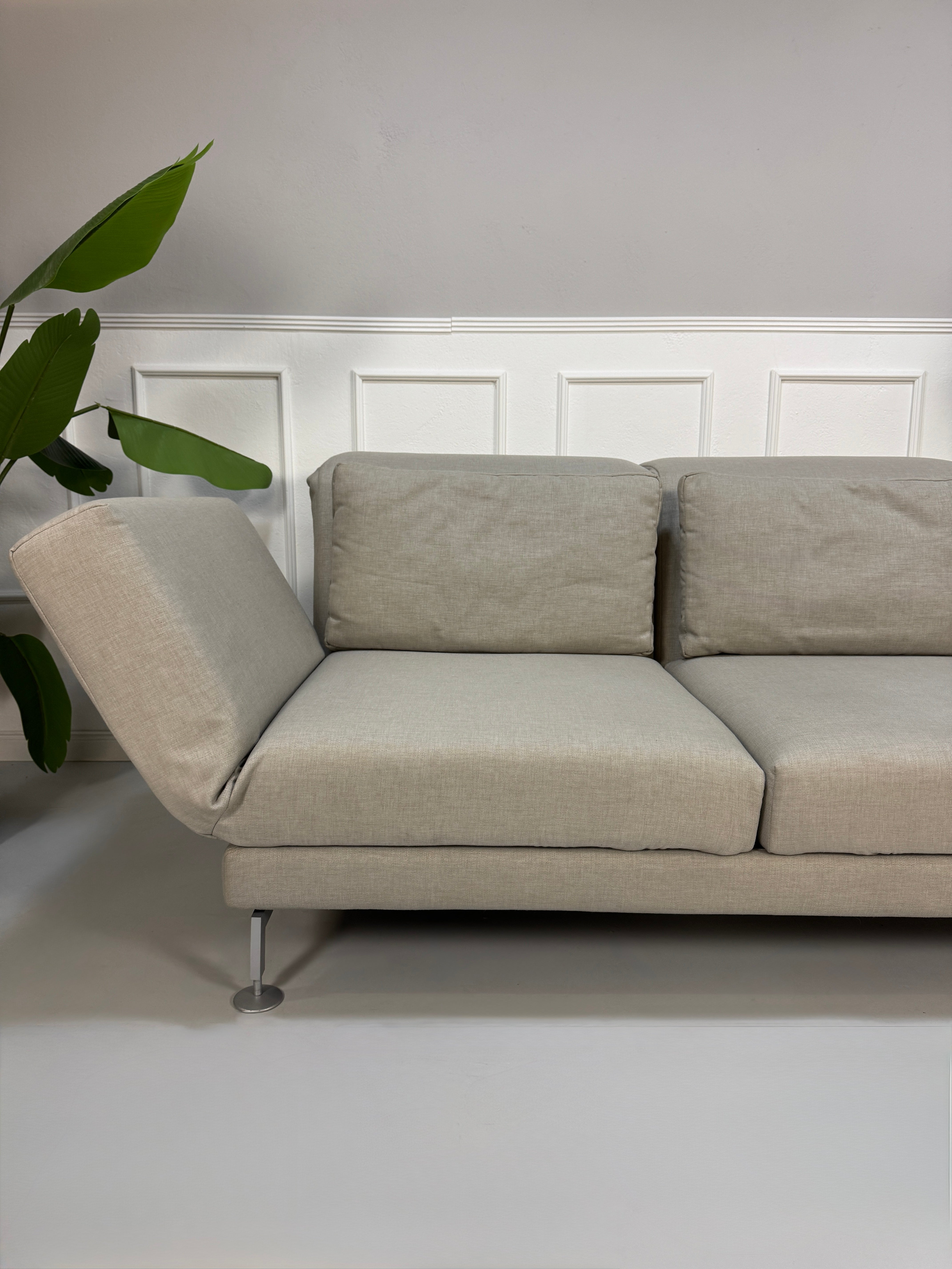 Gebrauchtes beiges Stoff Sofa Brühl Modell Moule vor einer modernen Wand.