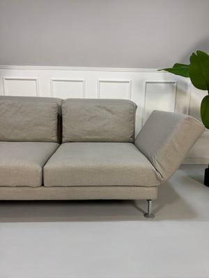 Gebrauchtes beiges Stoff Sofa Brühl Modell Moule vor einer modernen Wand.