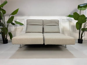 Gebrauchtes beiges Stoff Sofa Brühl Modell Moule vor einer modernen Wand.