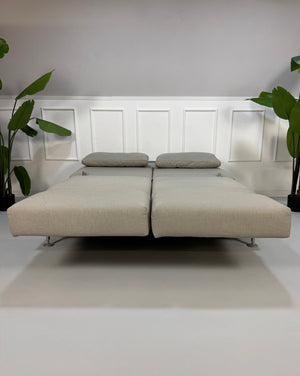 Gebrauchtes beiges Stoff Sofa Brühl Modell Moule vor einer modernen Wand.