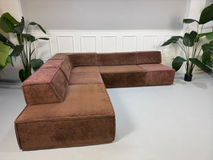 Gebrauchtes modulares braunes COR Trio Designer Stoff Sofa vor einer Wand, stilvoll und modern eingerichtet.