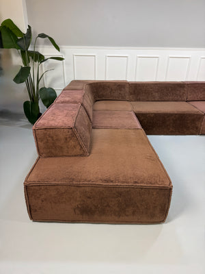 Gebrauchtes modulares braunes COR Trio Designer Stoff Sofa vor einer Wand, stilvoll und modern eingerichtet.