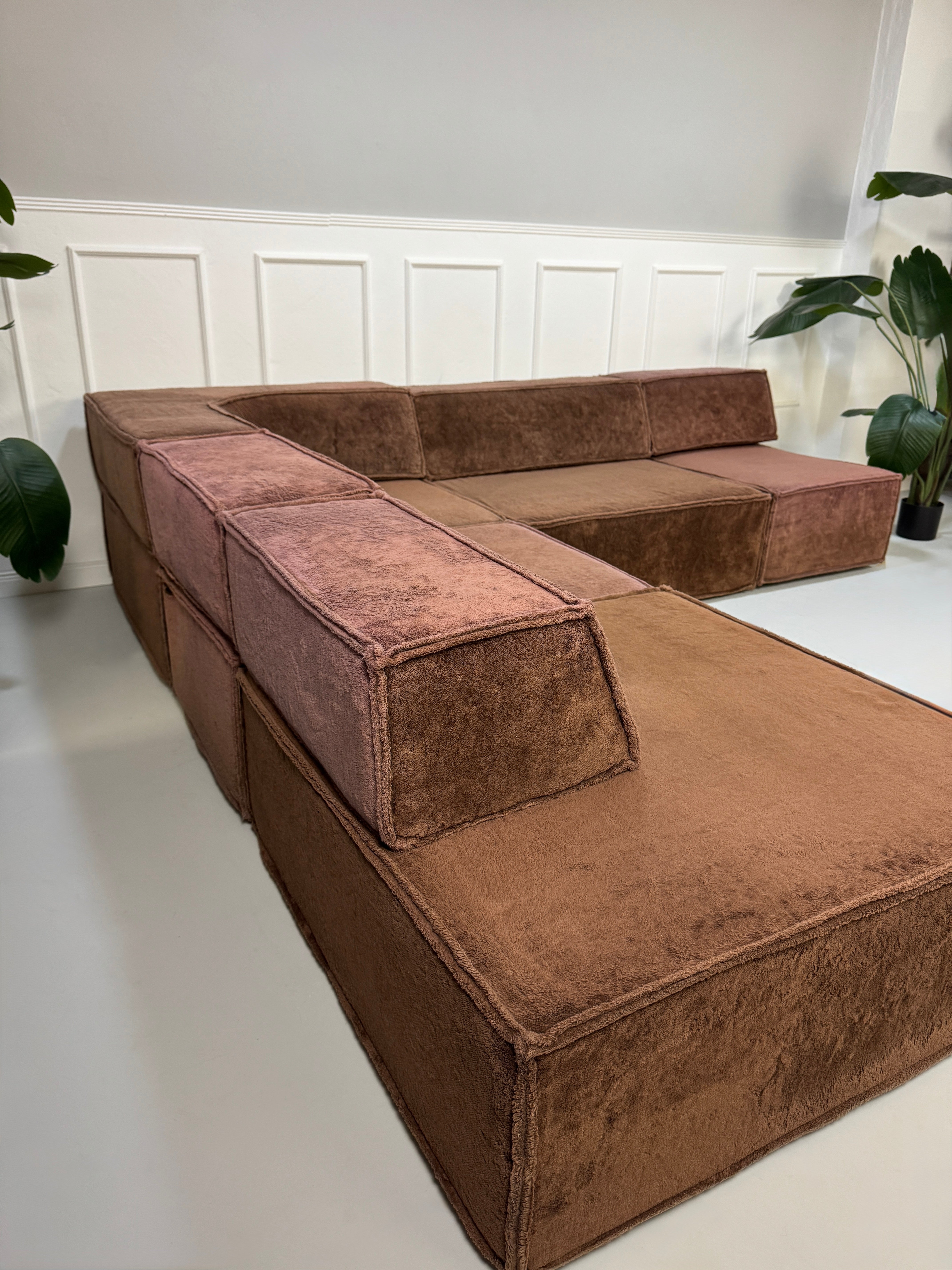 Gebrauchtes modulares braunes COR Trio Designer Stoff Sofa vor einer Wand, stilvoll und modern eingerichtet.