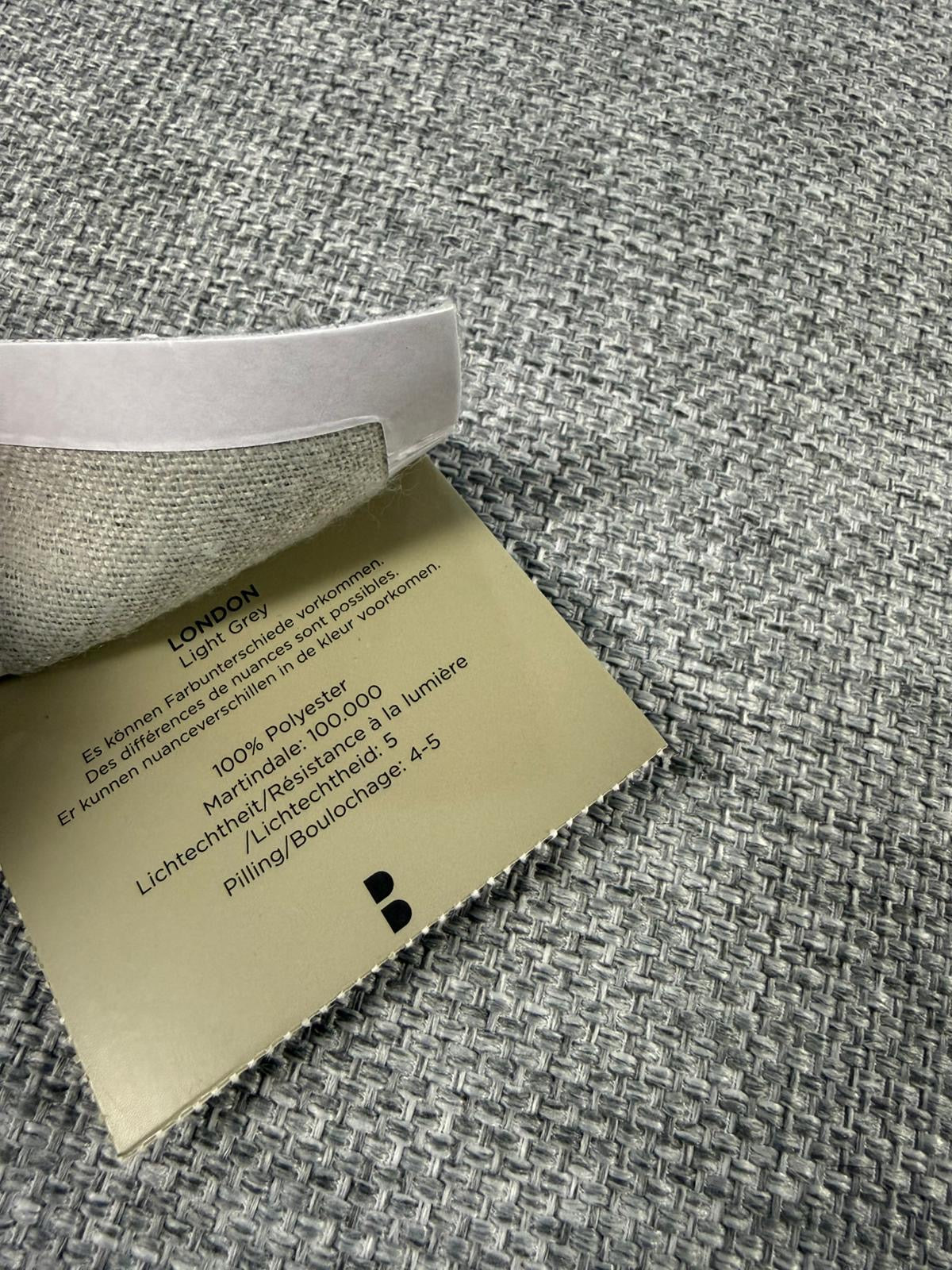 Refurbished graues Bolia Scandinavia Designer Stoff Sofa mit Hocker vor einer Wand, stilvoll und modern eingerichtet.