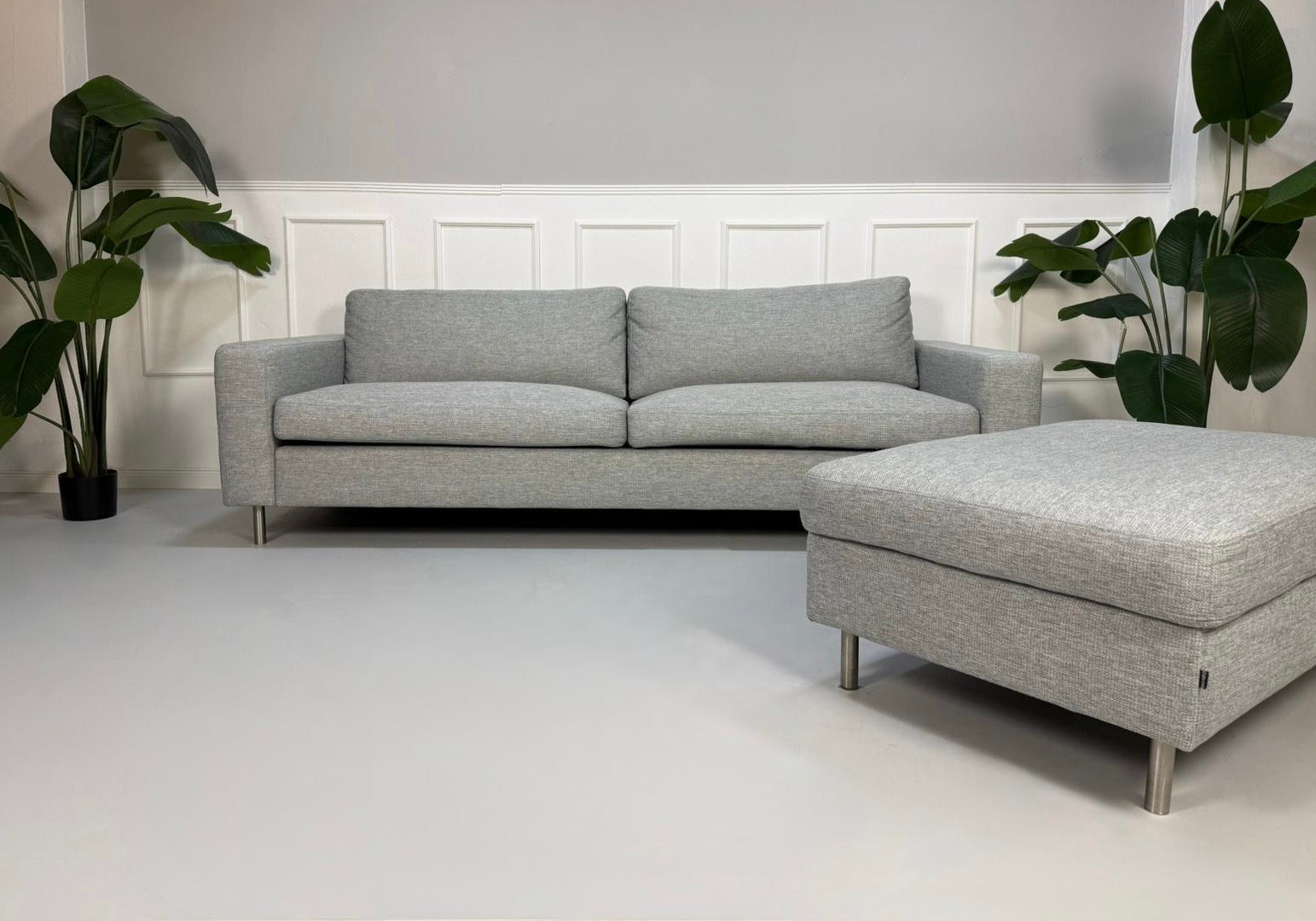 Refurbished graues Bolia Scandinavia Designer Stoff Sofa mit Hocker vor einer Wand, stilvoll und modern eingerichtet.