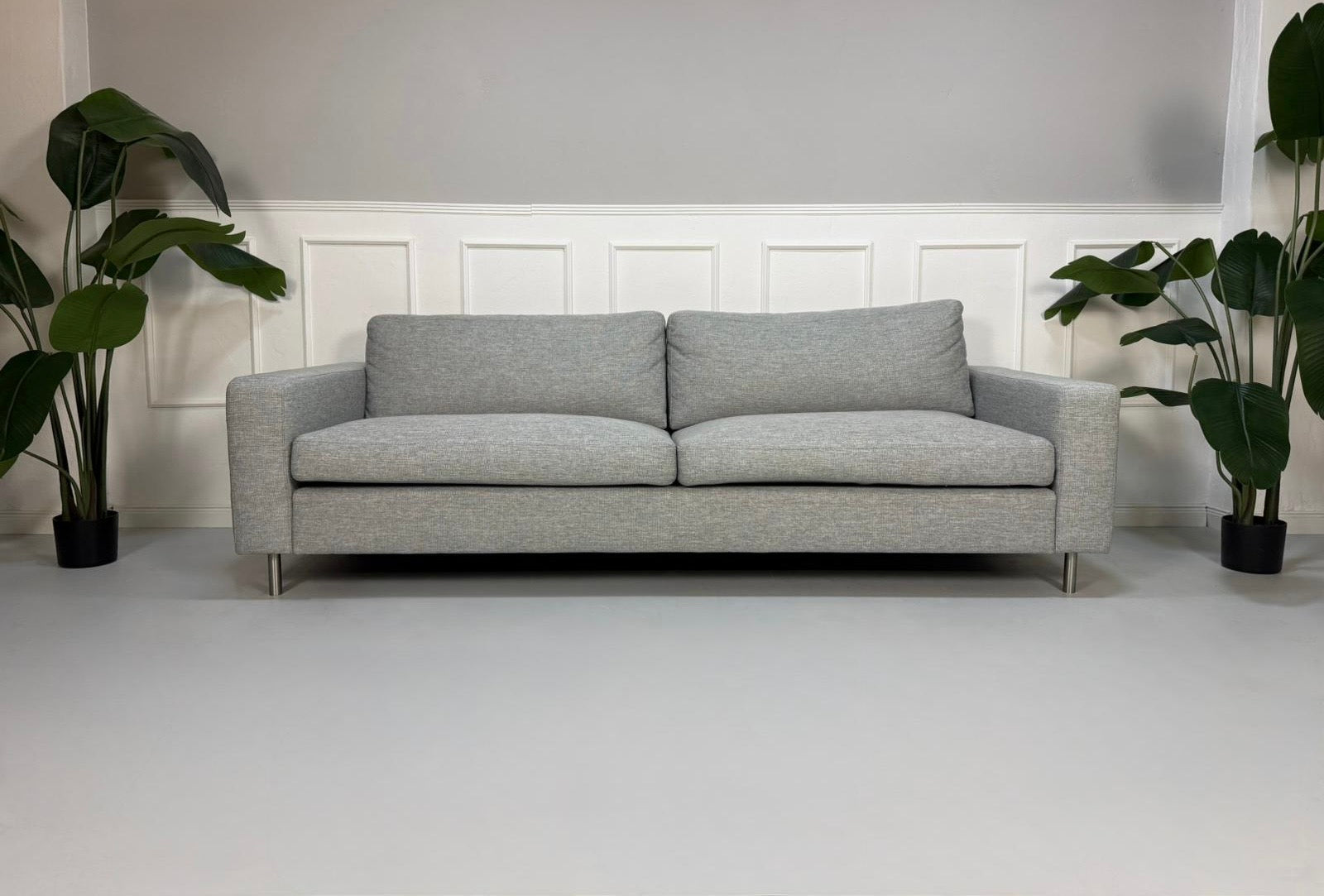 Refurbished graues Bolia Scandinavia Designer Stoff Sofa mit Hocker vor einer Wand, stilvoll und modern eingerichtet.
