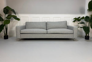 Refurbished graues Bolia Scandinavia Designer Stoff Sofa mit Hocker vor einer Wand, stilvoll und modern eingerichtet.