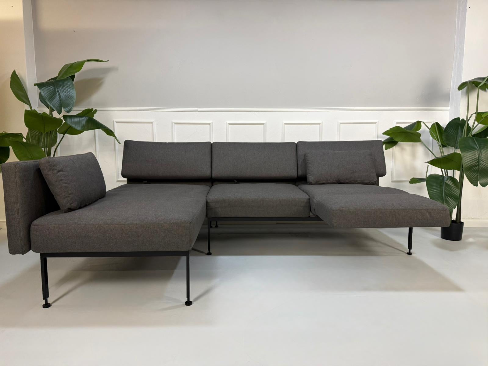 Gebrauchtes graues Brühl Roro Soft Designer Stoff Sofa vor einer Wand, stilvoll und modern eingerichtet.