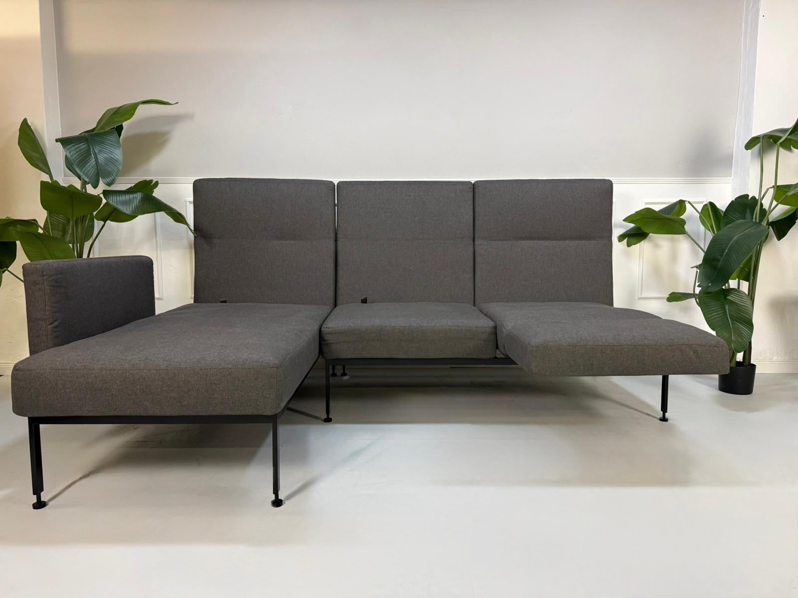 Gebrauchtes graues Brühl Roro Soft Designer Stoff Sofa vor einer Wand, stilvoll und modern eingerichtet.
