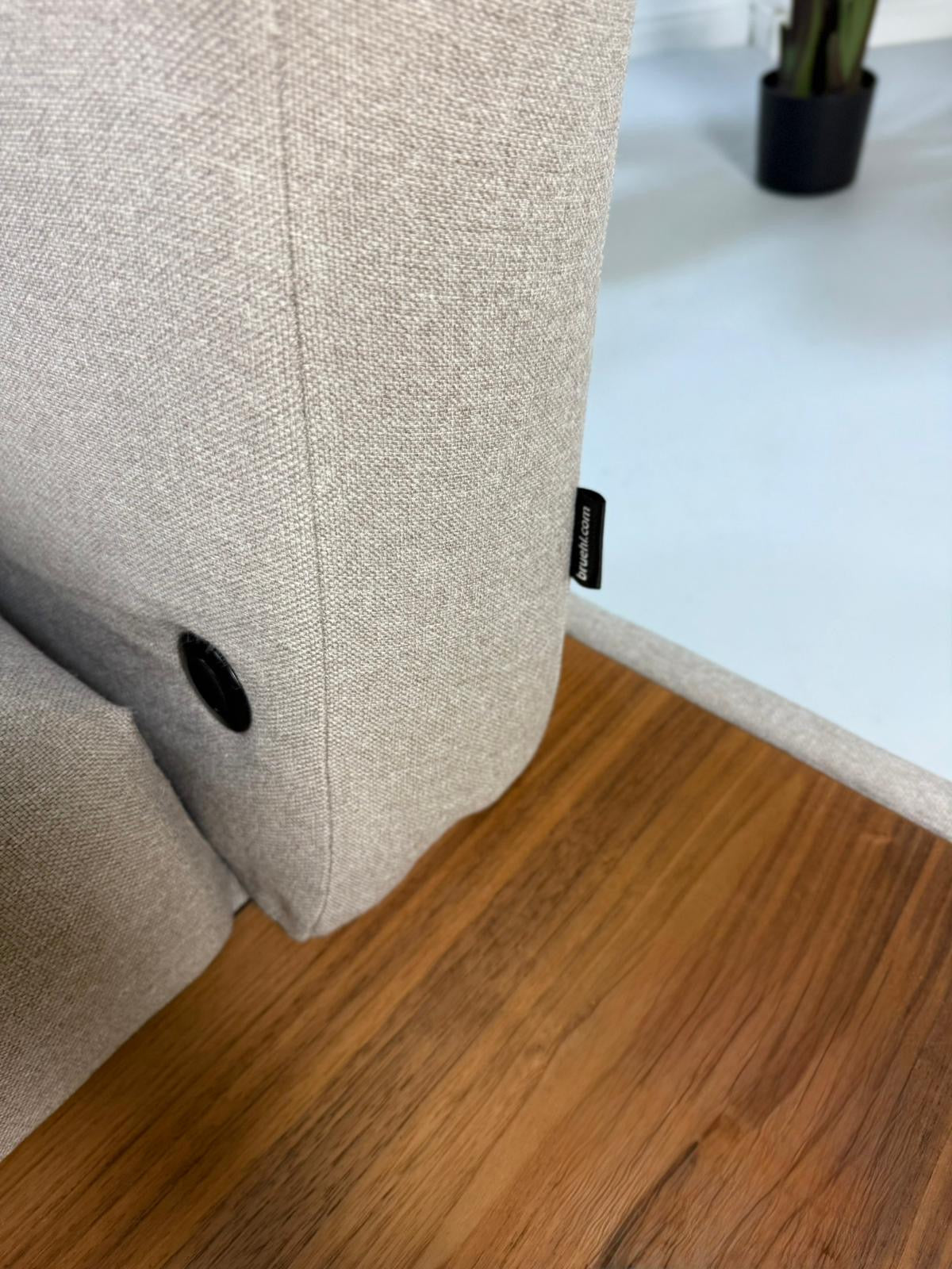 Gebrauchtes graues Brühl Moule Designer Stoff Sofa vor einer Wand, stilvoll und modern eingerichtet.