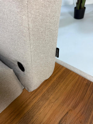 Gebrauchtes graues Brühl Moule Designer Stoff Sofa vor einer Wand, stilvoll und modern eingerichtet.