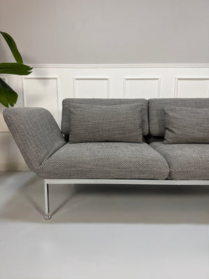 Gebrauchtes Brühl Roro Designer Stoff Sofa in der Farbe Grau vor einer Wand, stilvoll und modern eingerichtet.