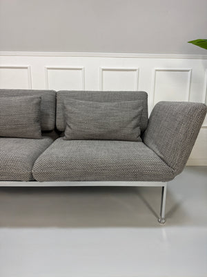 Gebrauchtes Brühl Roro Designer Stoff Sofa in der Farbe Grau vor einer Wand, stilvoll und modern eingerichtet.
