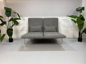 Gebrauchtes Brühl Roro Designer Stoff Sofa in der Farbe Grau vor einer Wand, stilvoll und modern eingerichtet.