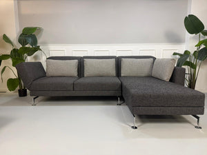 Gebrauchtes graues Brühl Moule Designer Stoff Sofa vor einer Wand, stilvoll und modern eingerichtet.