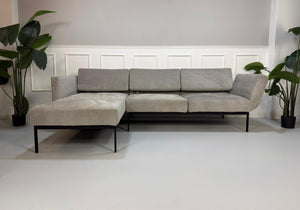 Gebrauchtes graues Brühl Roro Soft Designer Stoff Sofa vor einer Wand, stilvoll und modern eingerichtet.
