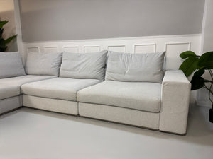 Erneuertes Flexform Groundpiece Designer Stoff Sofa vor einer Wand, stilvoll und modern eingerichtet.