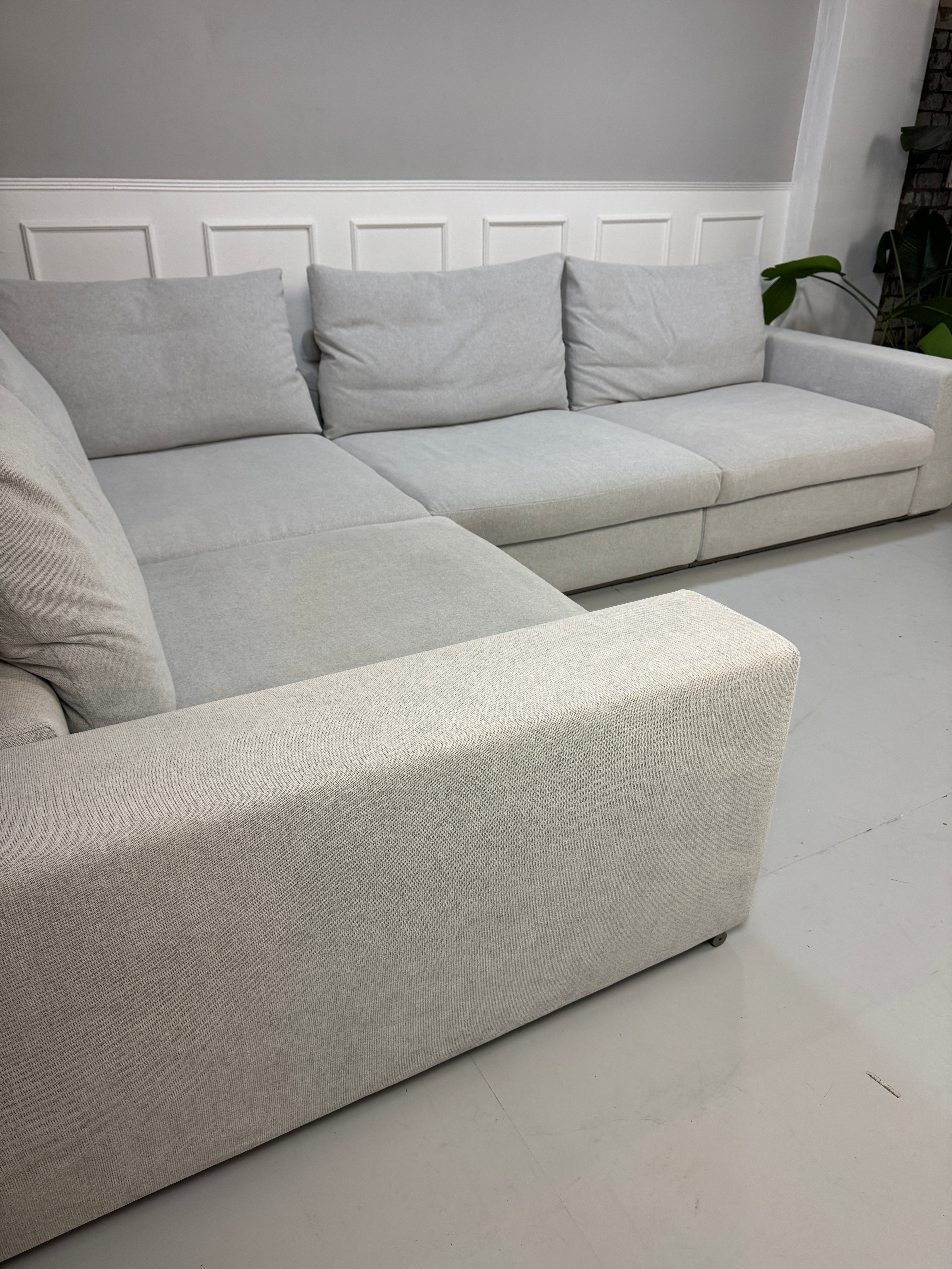 Erneuertes Flexform Groundpiece Designer Stoff Sofa vor einer Wand, stilvoll und modern eingerichtet.