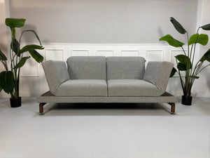Gebrauchtes Brühl Moule Designer Stoff Sofa in der Farbe Grau vor einer Wand, stilvoll und modern eingerichtet.