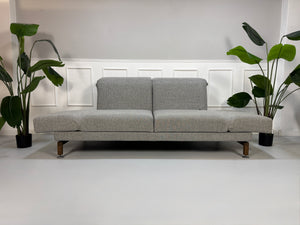 Gebrauchtes Brühl Moule Designer Stoff Sofa in der Farbe Grau vor einer Wand, stilvoll und modern eingerichtet.