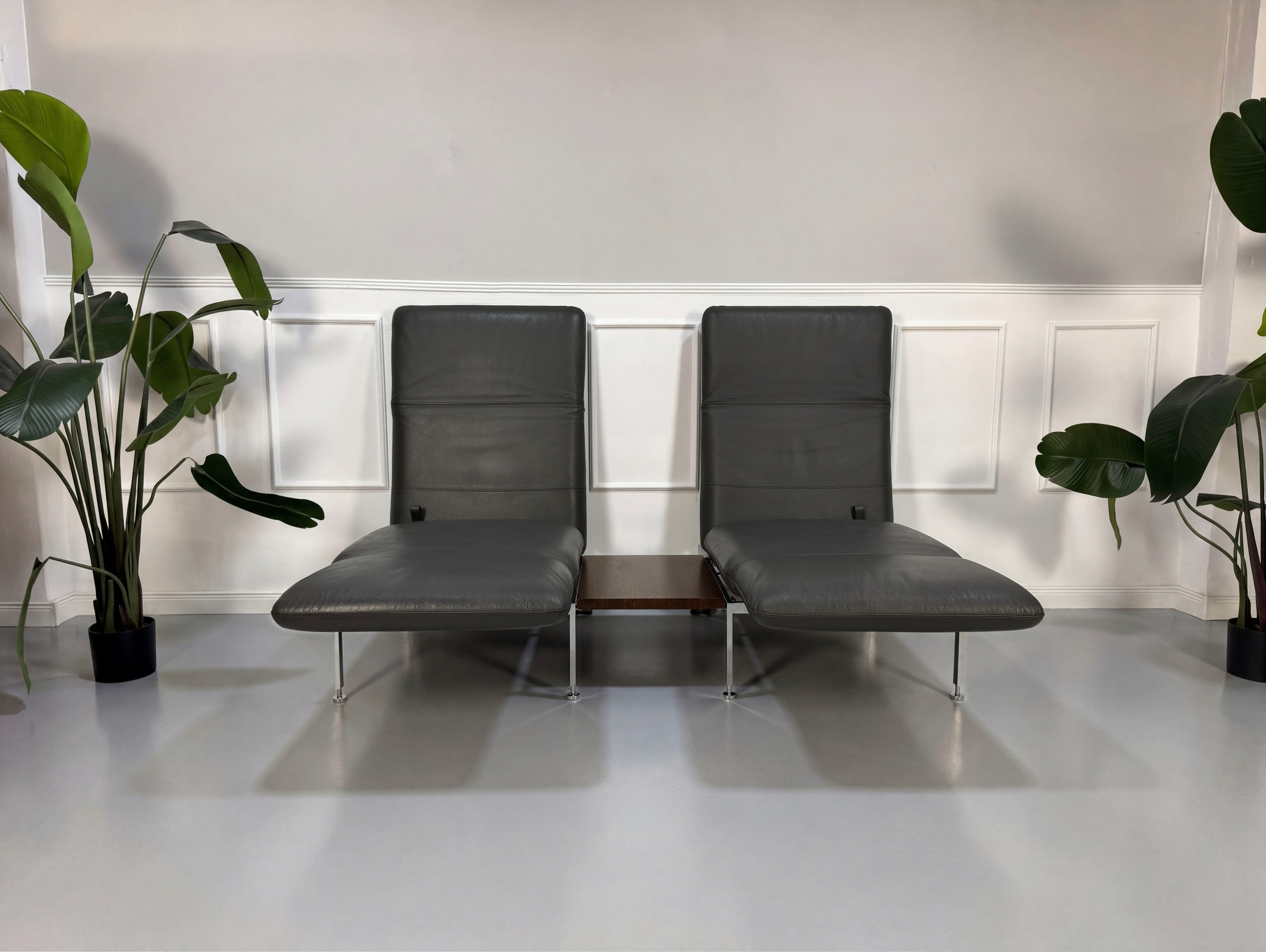Gebrauchtes graues Brühl Roro Designer Leder Sofa mit Tisch vor einer Wand, stilvoll und modern eingerichtet.