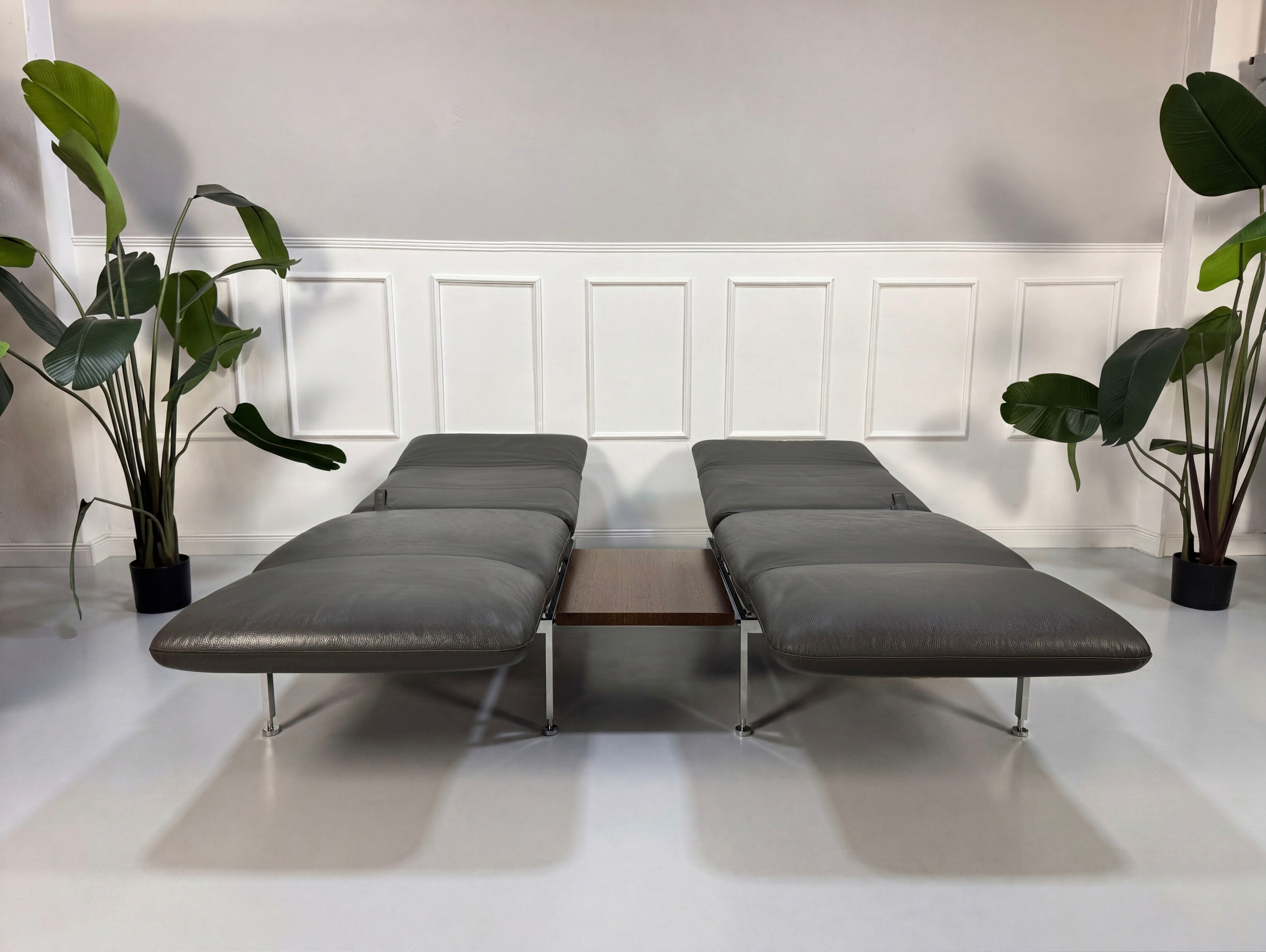 Gebrauchtes graues Brühl Roro Designer Leder Sofa mit Tisch vor einer Wand, stilvoll und modern eingerichtet.