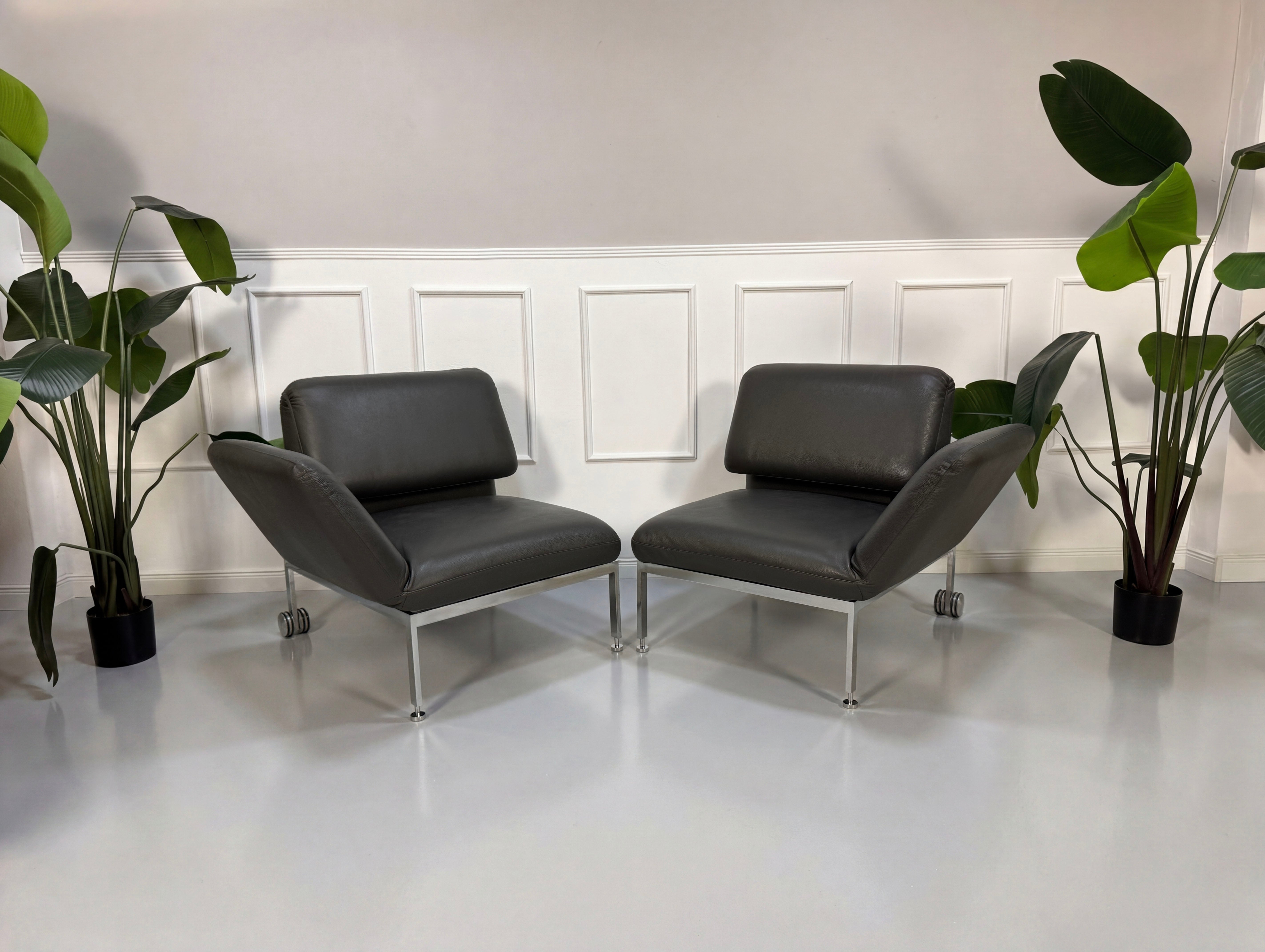 Gebrauchtes graues Brühl Roro Designer Leder Sofa mit Tisch vor einer Wand, stilvoll und modern eingerichtet.