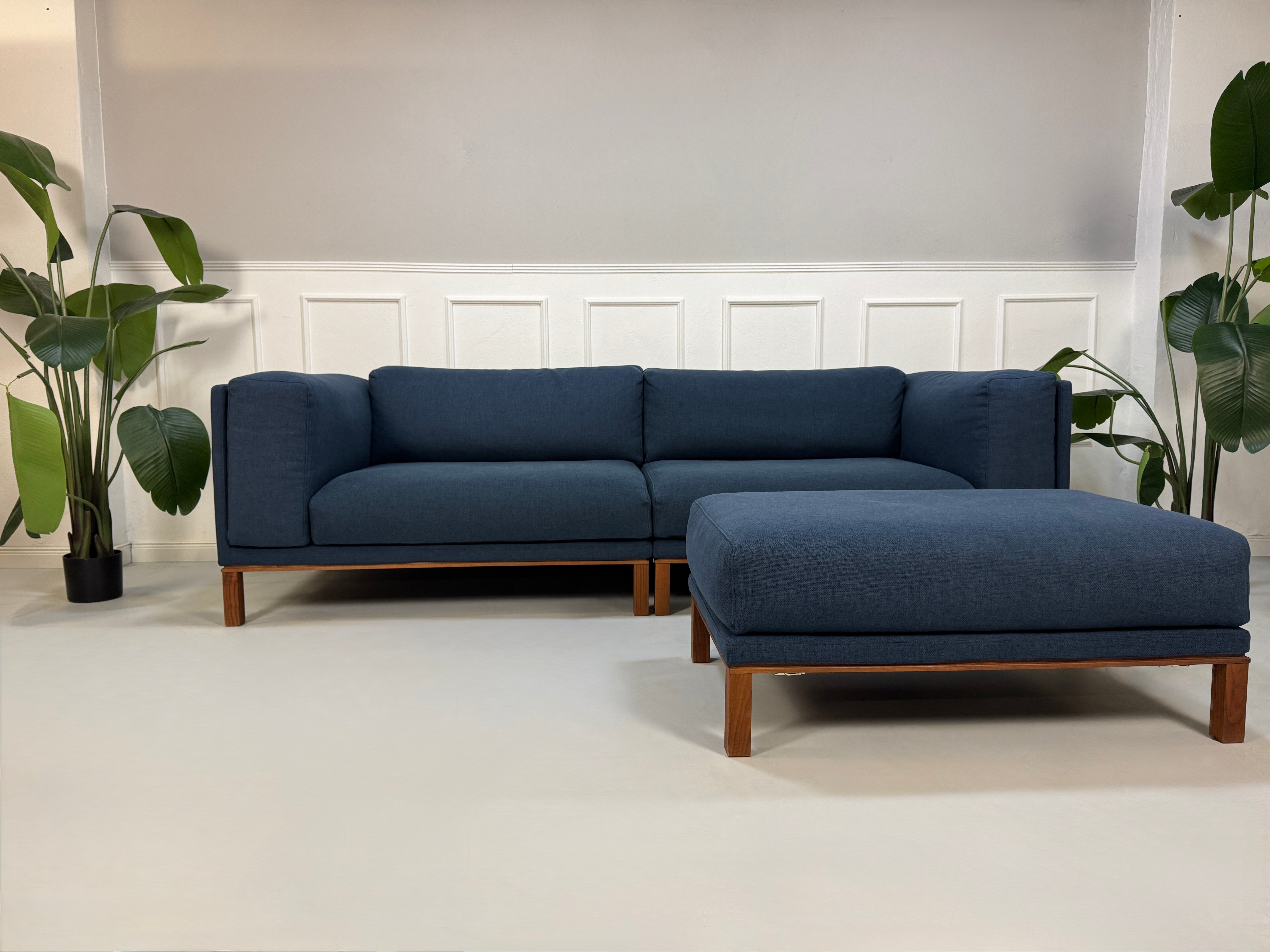 Gebrauchtes Bolia Cosy Designer Stoff Sofa in der Farbe Blau mit einem Hocker  vor einer Wand, stilvoll und modern eingerichtet.