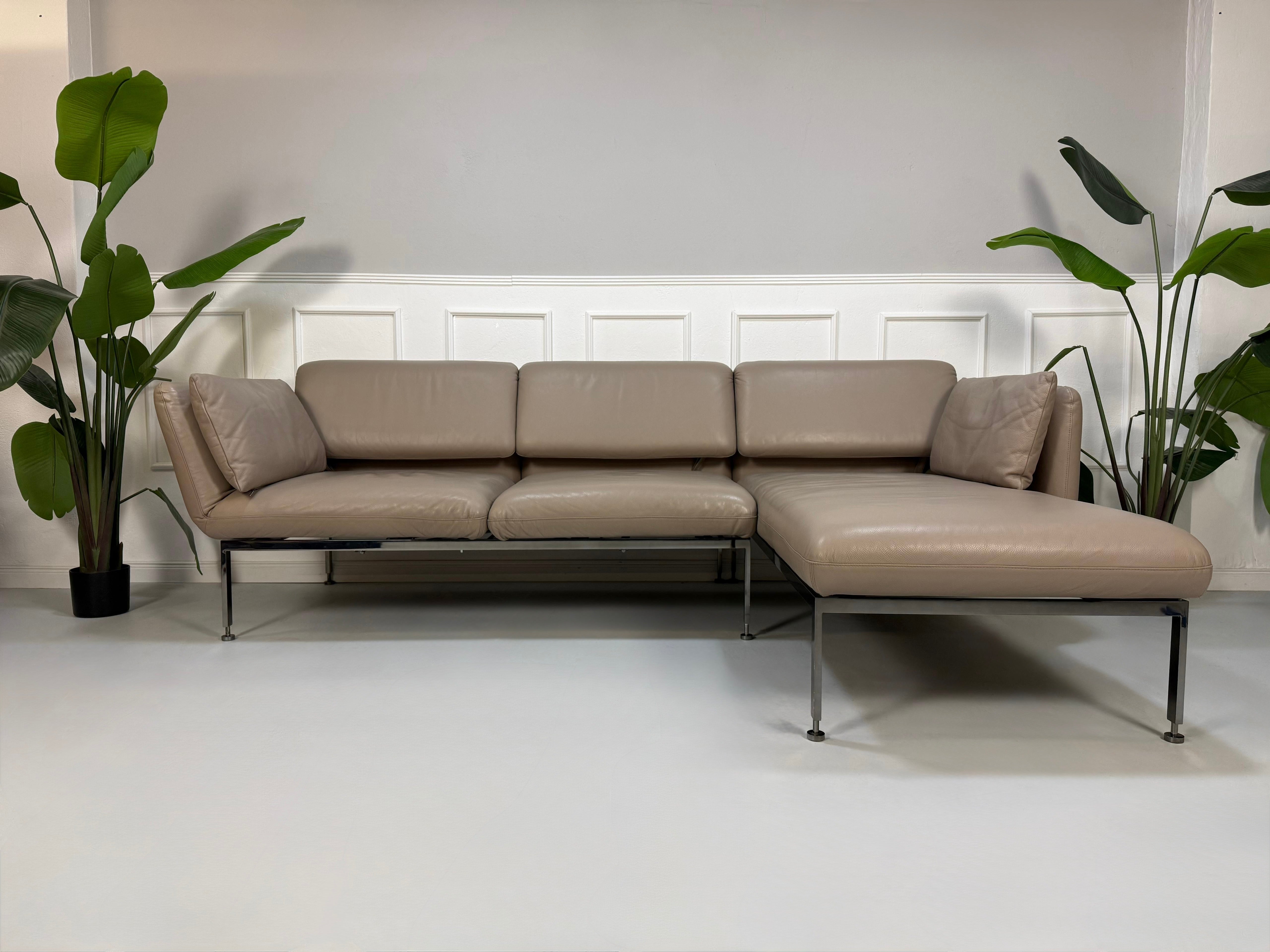 Gebrauchtes Brühl Roro Designer Leder Ecksofa in der Farbe Schlamm vor einer Wand, stilvoll und modern eingerichtet.