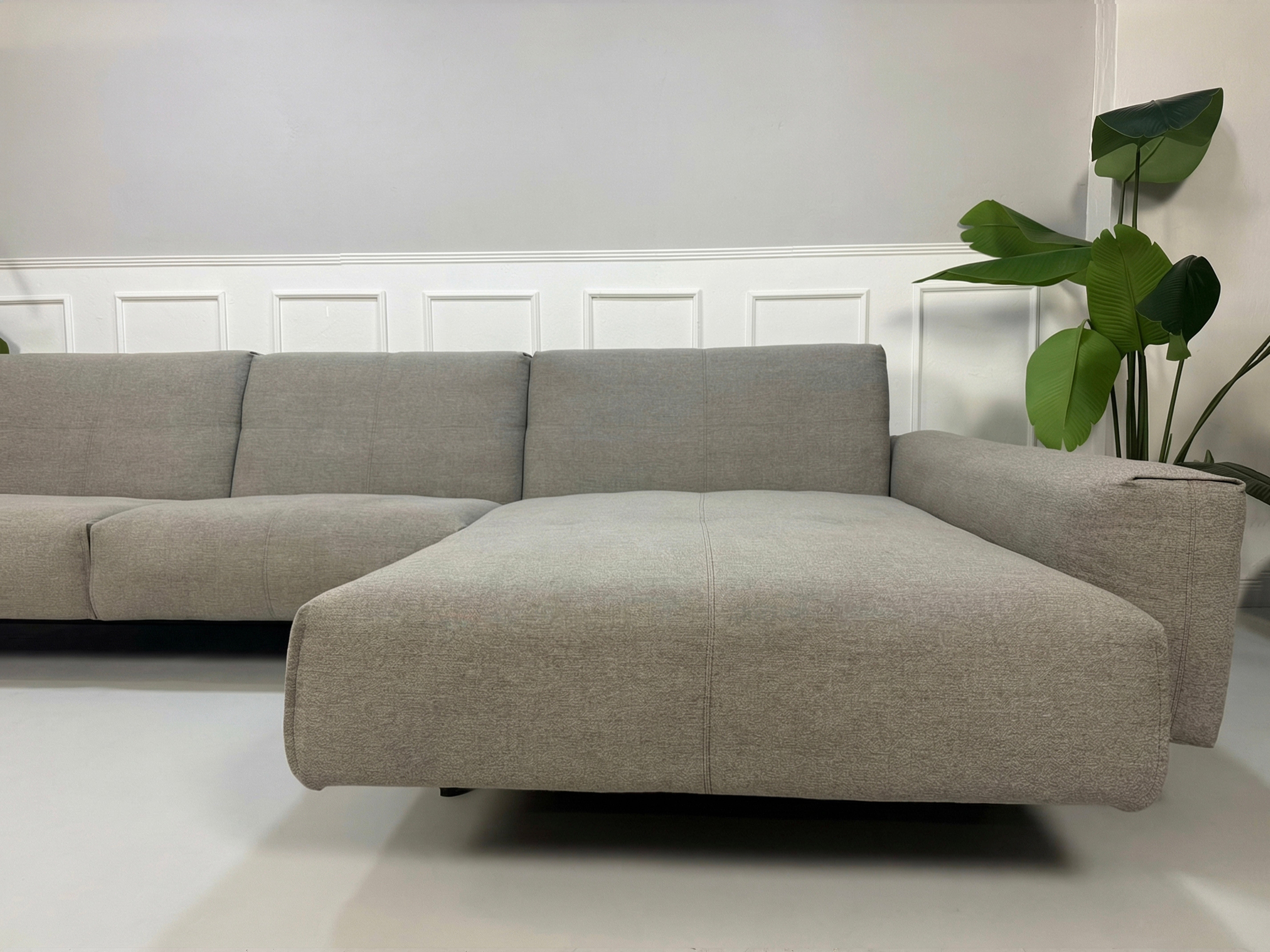 Gebrauchtes graues Rolf Benz 50 Designer Stoff Sofa vor einer Wand, stilvoll und modern eingerichtet.