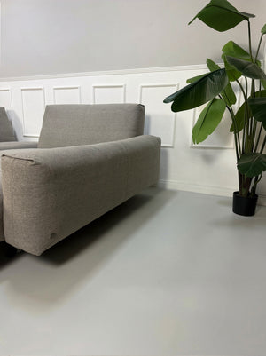 Gebrauchtes graues Rolf Benz 50 Designer Stoff Sofa vor einer Wand, stilvoll und modern eingerichtet.