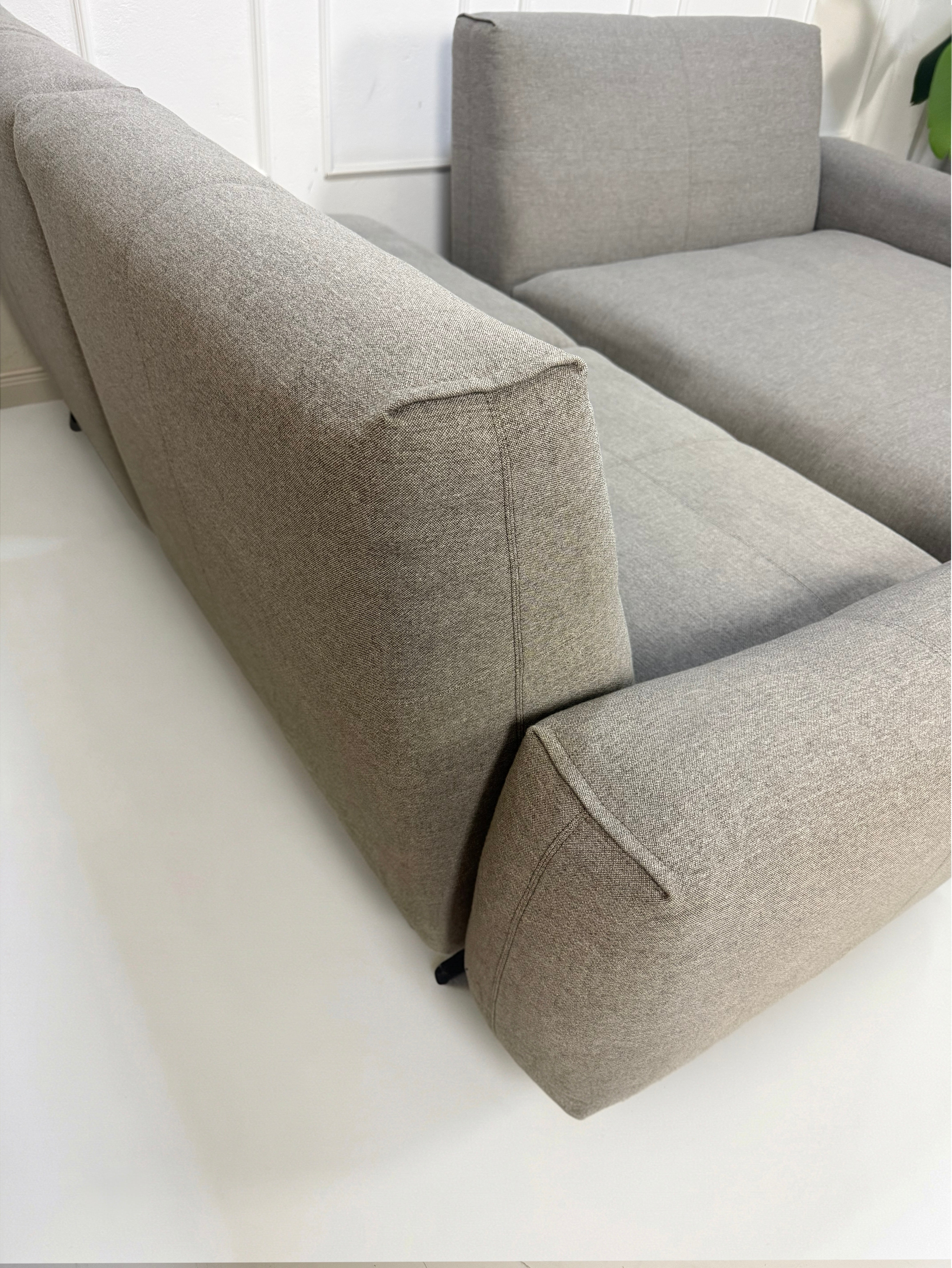 Gebrauchtes graues Rolf Benz 50 Designer Stoff Sofa vor einer Wand, stilvoll und modern eingerichtet.