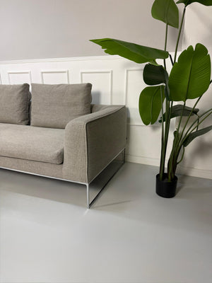 Gebrauchtes graues COR Mell Lounge Designer Stoff Sofa vor einer Wand, stilvoll und modern eingerichtet.