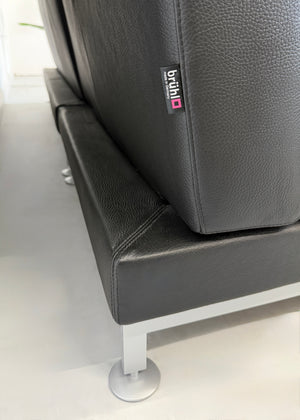 Refurbished Brühl Moule Designer Leder Sofa vor einer Wand, stilvoll und modern eingerichtet.