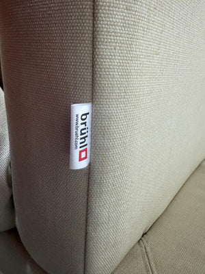 Gebrauchtes  Designer Stoff Sofa vor einer Wand, stilvoll und modern eingerichtet.