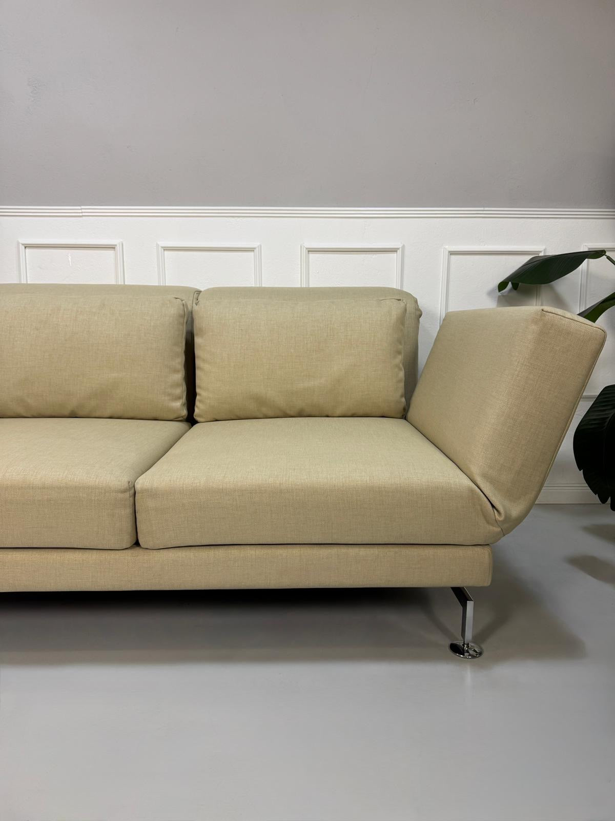 Gebrauchtes  Designer Stoff Sofa vor einer Wand, stilvoll und modern eingerichtet.