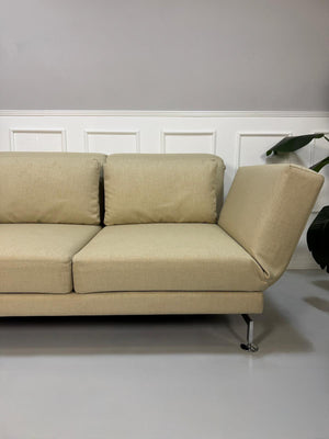 Gebrauchtes  Designer Stoff Sofa vor einer Wand, stilvoll und modern eingerichtet.