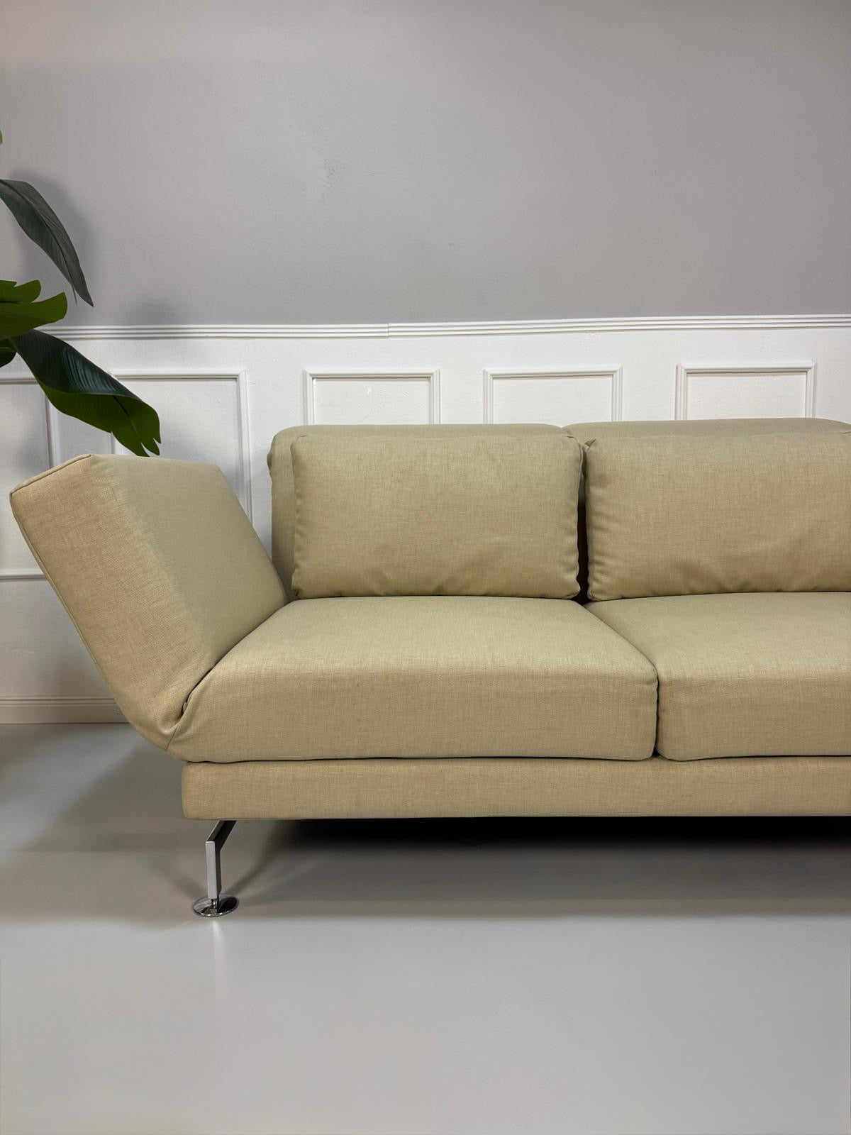 Gebrauchtes  Designer Stoff Sofa vor einer Wand, stilvoll und modern eingerichtet.