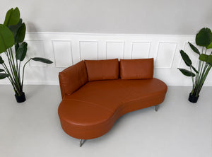 Ausstellungsstück von DeSede in braunem Leder vor einer Wand, stilvoll und modern eingerichtet.