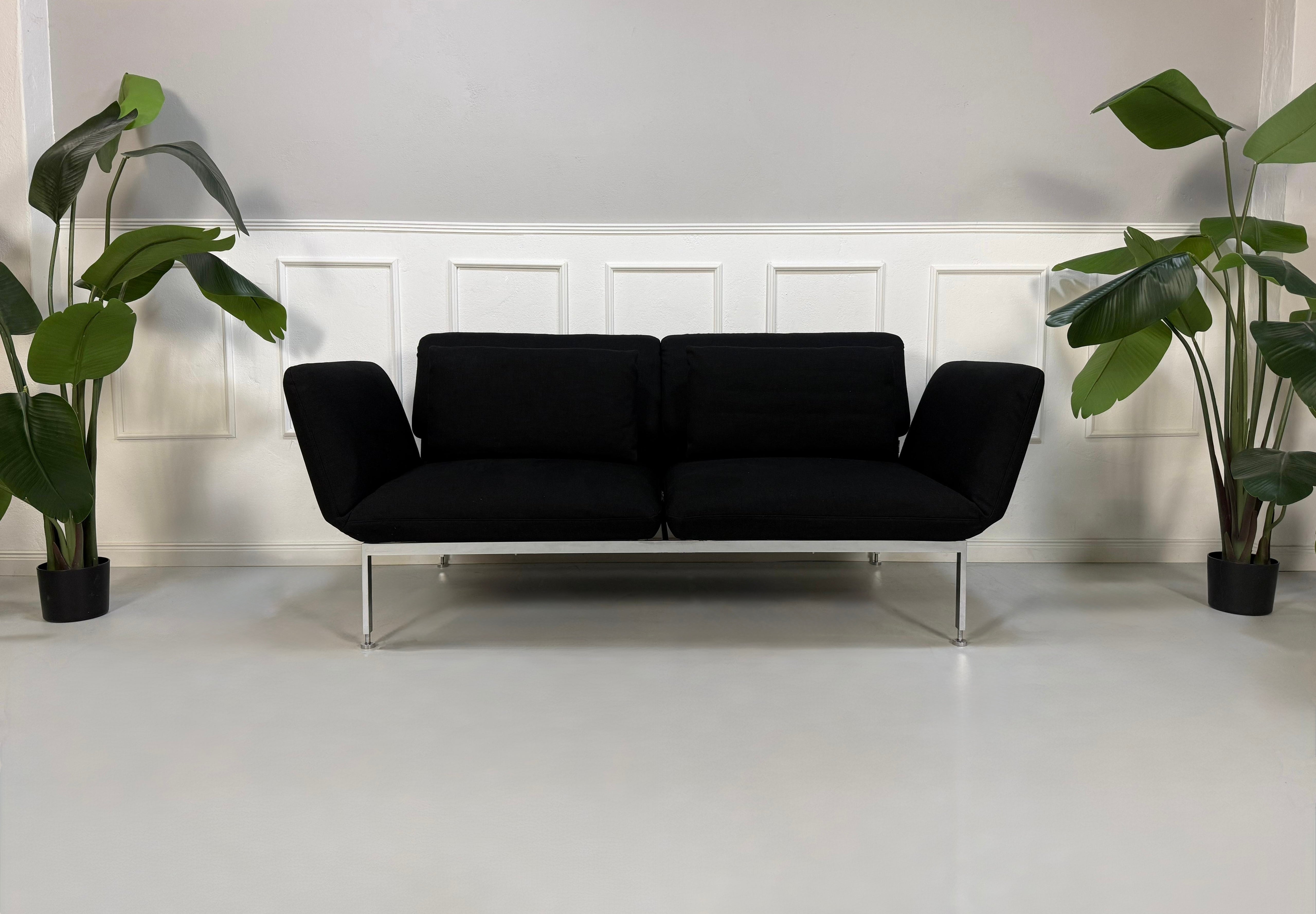 Gebrauchtes schwarzes Brühl Roro Designer Stoff Sofa vor einer Wand, stilvoll und modern eingerichtet.