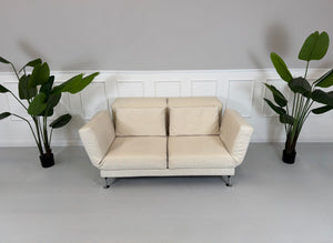 Gebrauchtes beiges Brühl Moule Designer Stoff Sofa vor einer Wand, stilvoll und modern eingerichtet.