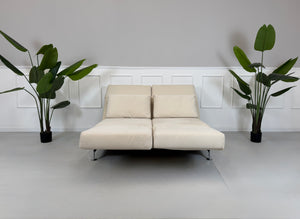 Gebrauchtes beiges Brühl Moule Designer Stoff Sofa vor einer Wand, stilvoll und modern eingerichtet.