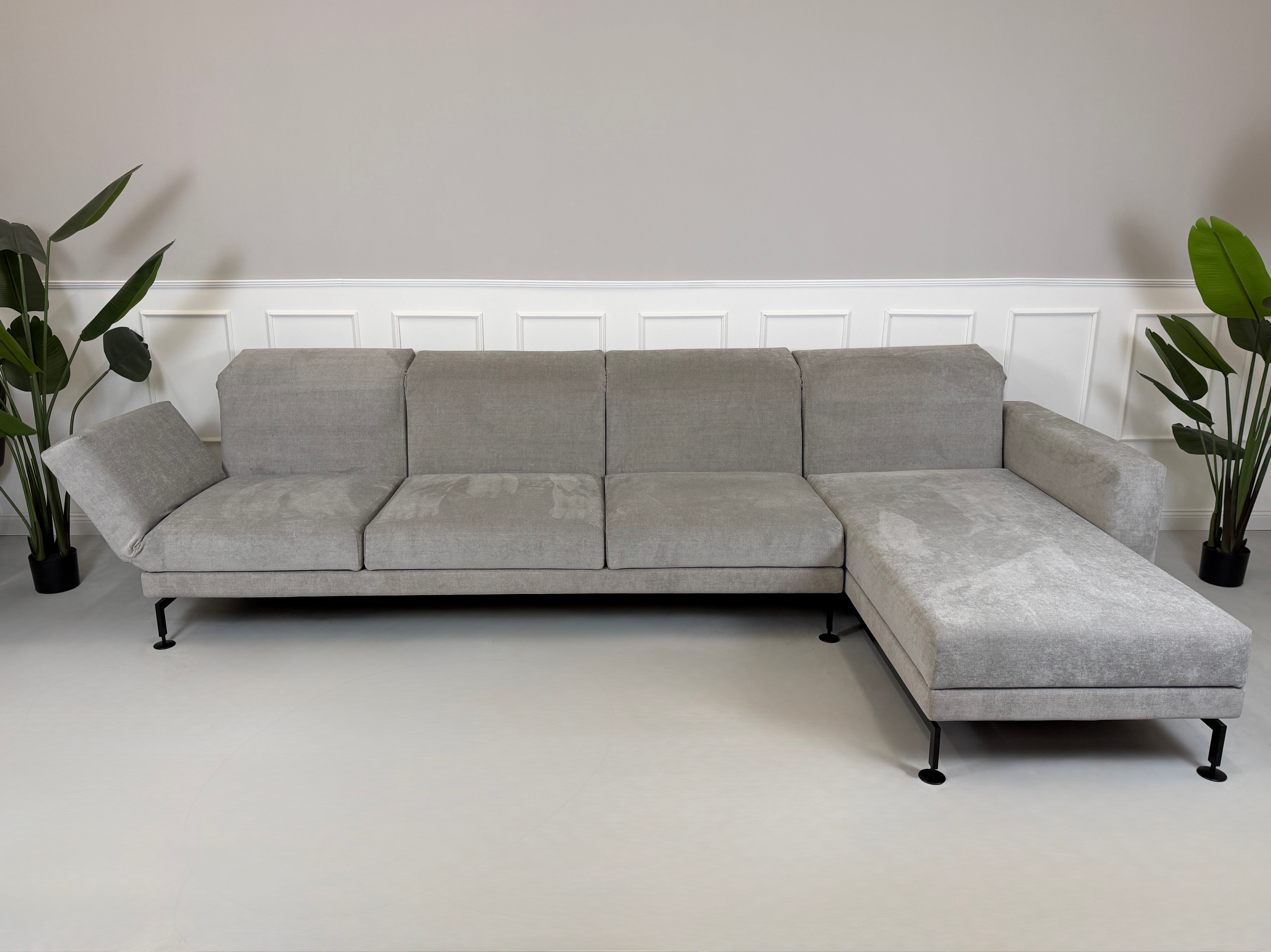 Graues Ausstellungsstück Brühl Moule Designer Stoff Sofa vor einer Wand, stilvoll und modern eingerichtet.