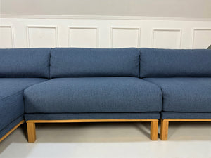 Gebrauchtes blaues Bolia Cosy Designer Stoff Sofa vor einer Wand, stilvoll und modern eingerichtet.