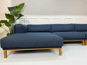 Gebrauchtes blaues Bolia Cosy Designer Stoff Sofa vor einer Wand, stilvoll und modern eingerichtet.