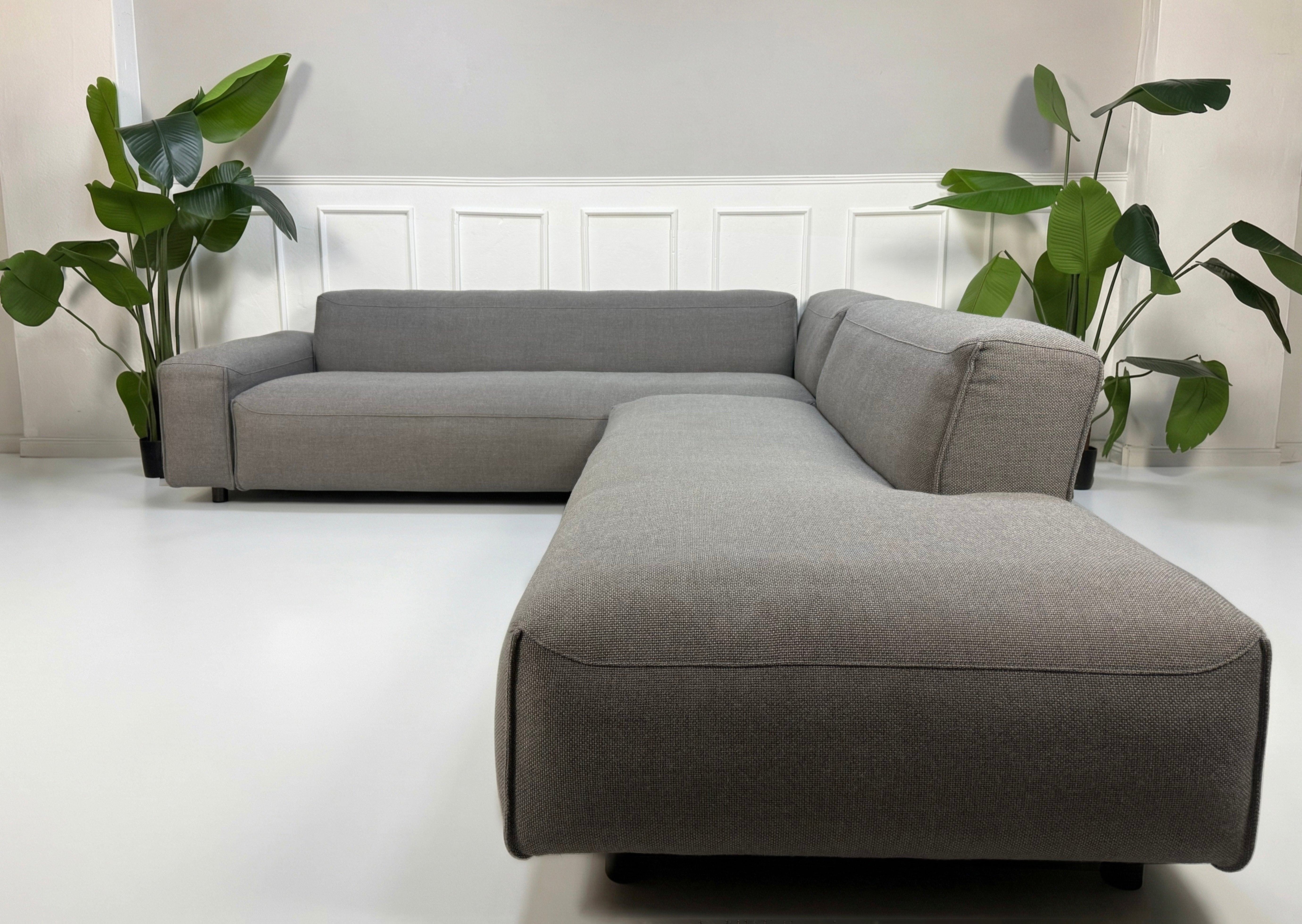 Erneuertes graues Rolf Benz Mio Designer Stoff Sofa vor einer Wand, stilvoll und modern eingerichtet.