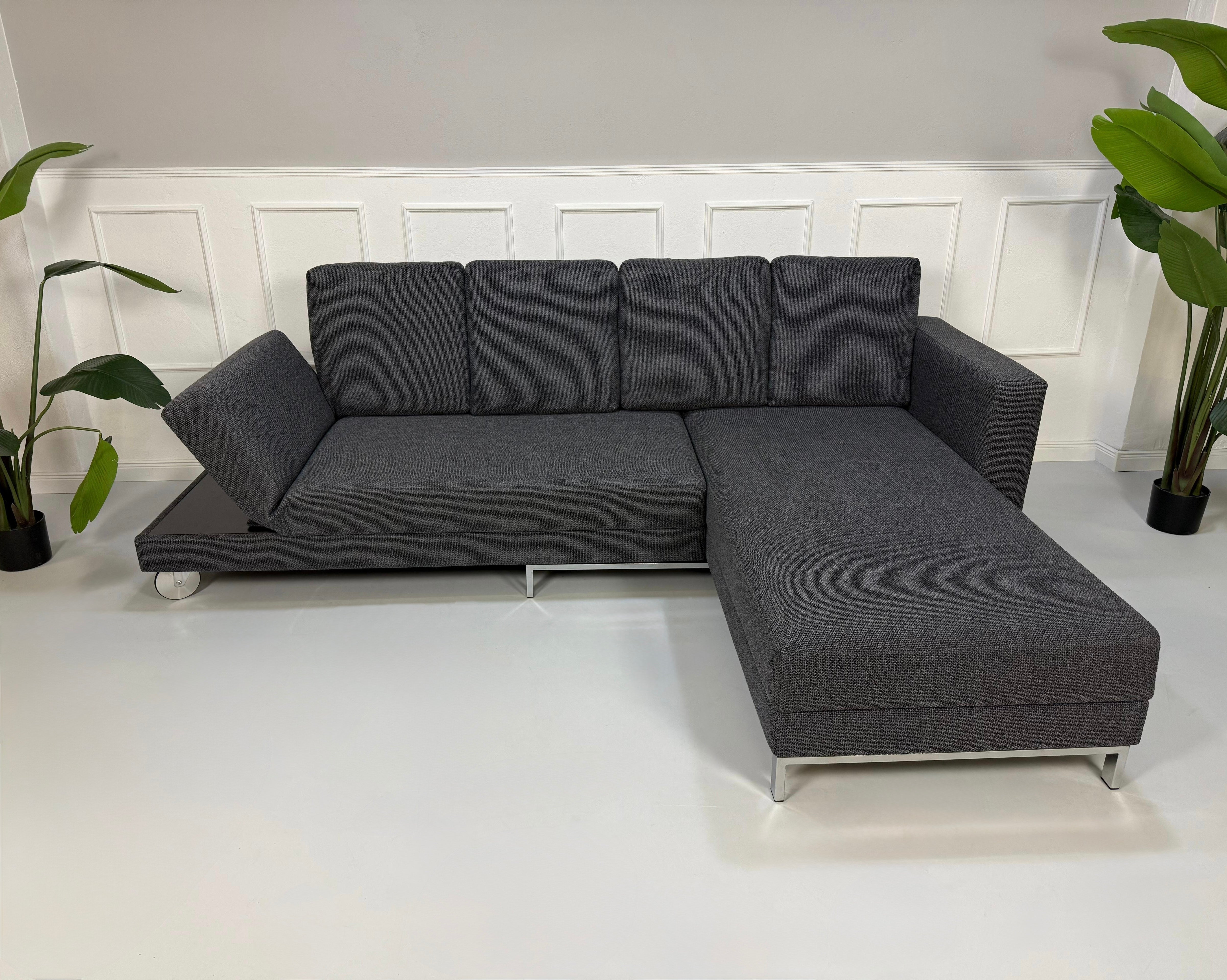 Gebrauchtes graues Brühl Four Two Designer Stoff Sofa vor einer Wand, stilvoll und modern eingerichtet.
