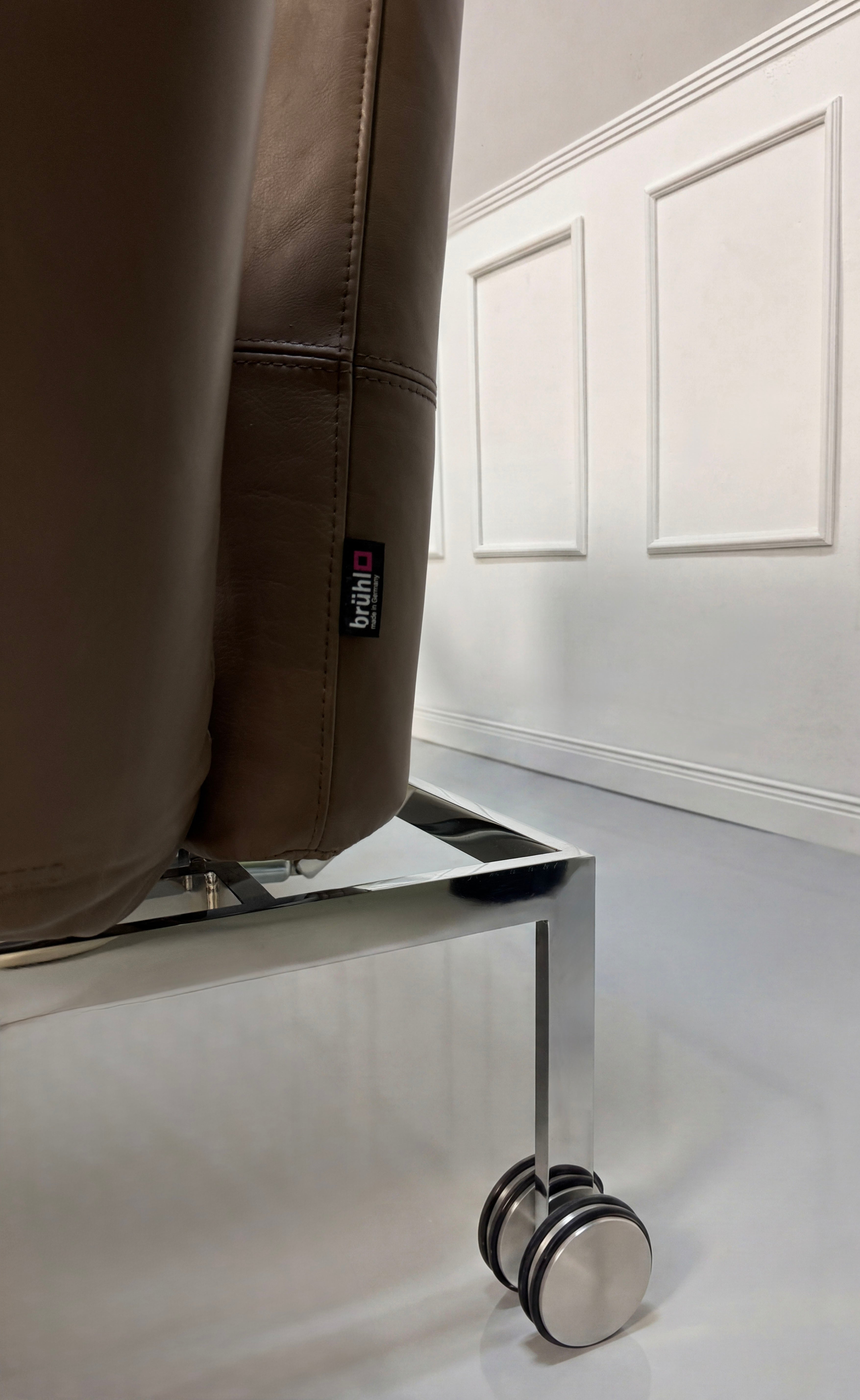 Gebrauchtes braunes Brühl Roro Designer Leder Sofa vor einer Wand, stilvoll und modern eingerichtet.