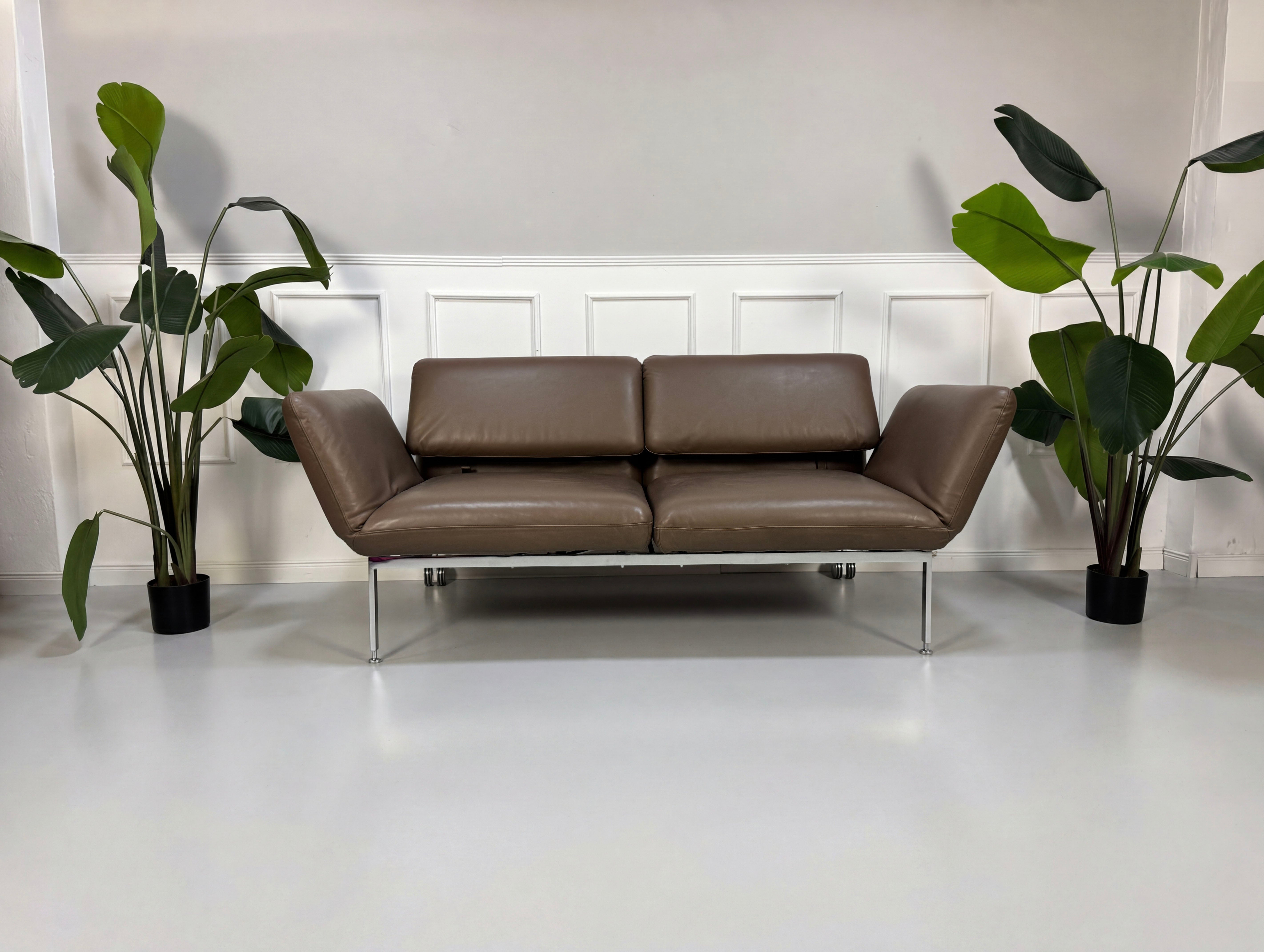 Gebrauchtes braunes Brühl Roro Designer Leder Sofa vor einer Wand, stilvoll und modern eingerichtet.