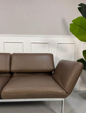 Gebrauchtes braunes Brühl Roro Designer Leder Sofa vor einer Wand, stilvoll und modern eingerichtet.